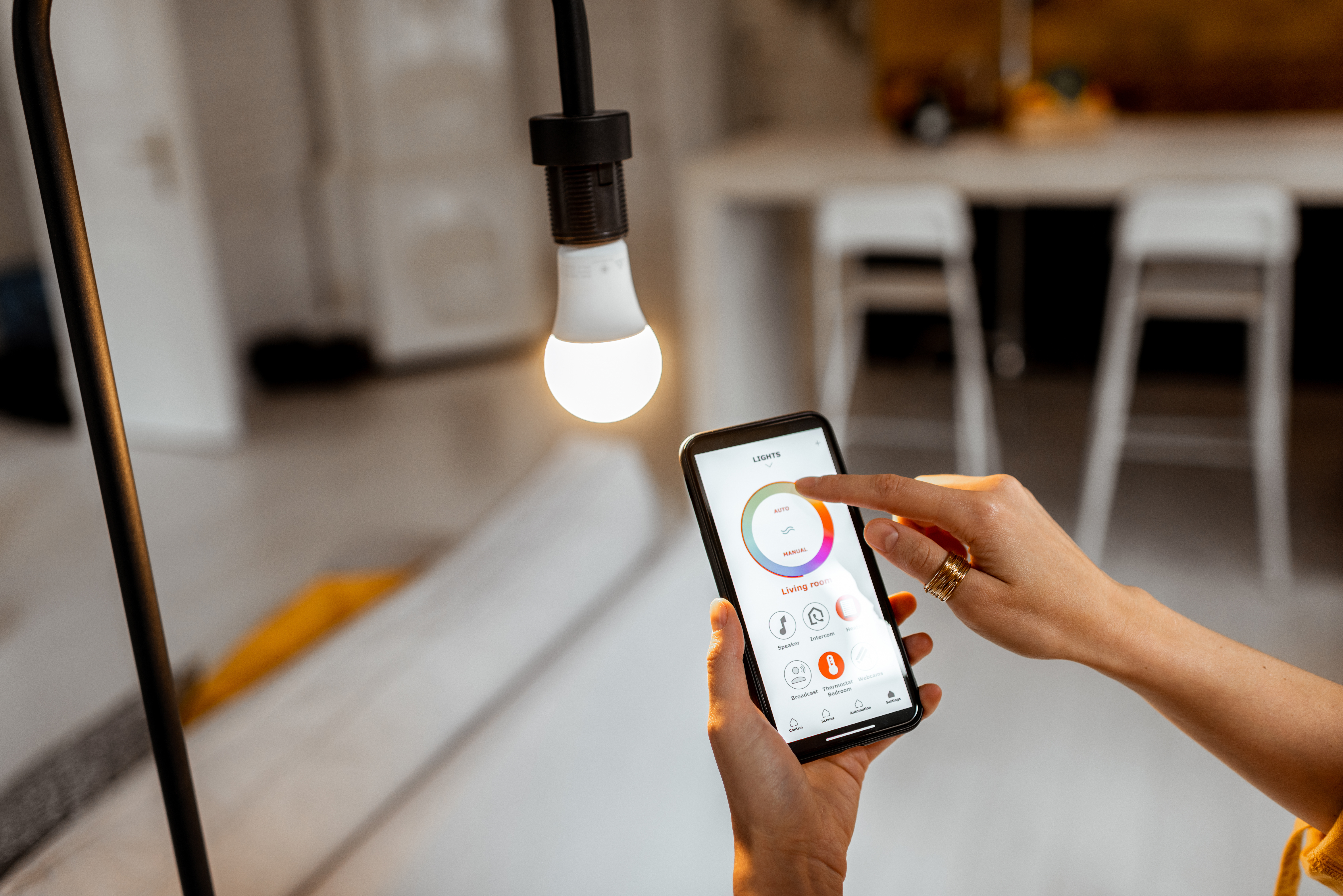 Bilde av en lyspære og en mobiltelefon som styrer smartlys hjemme