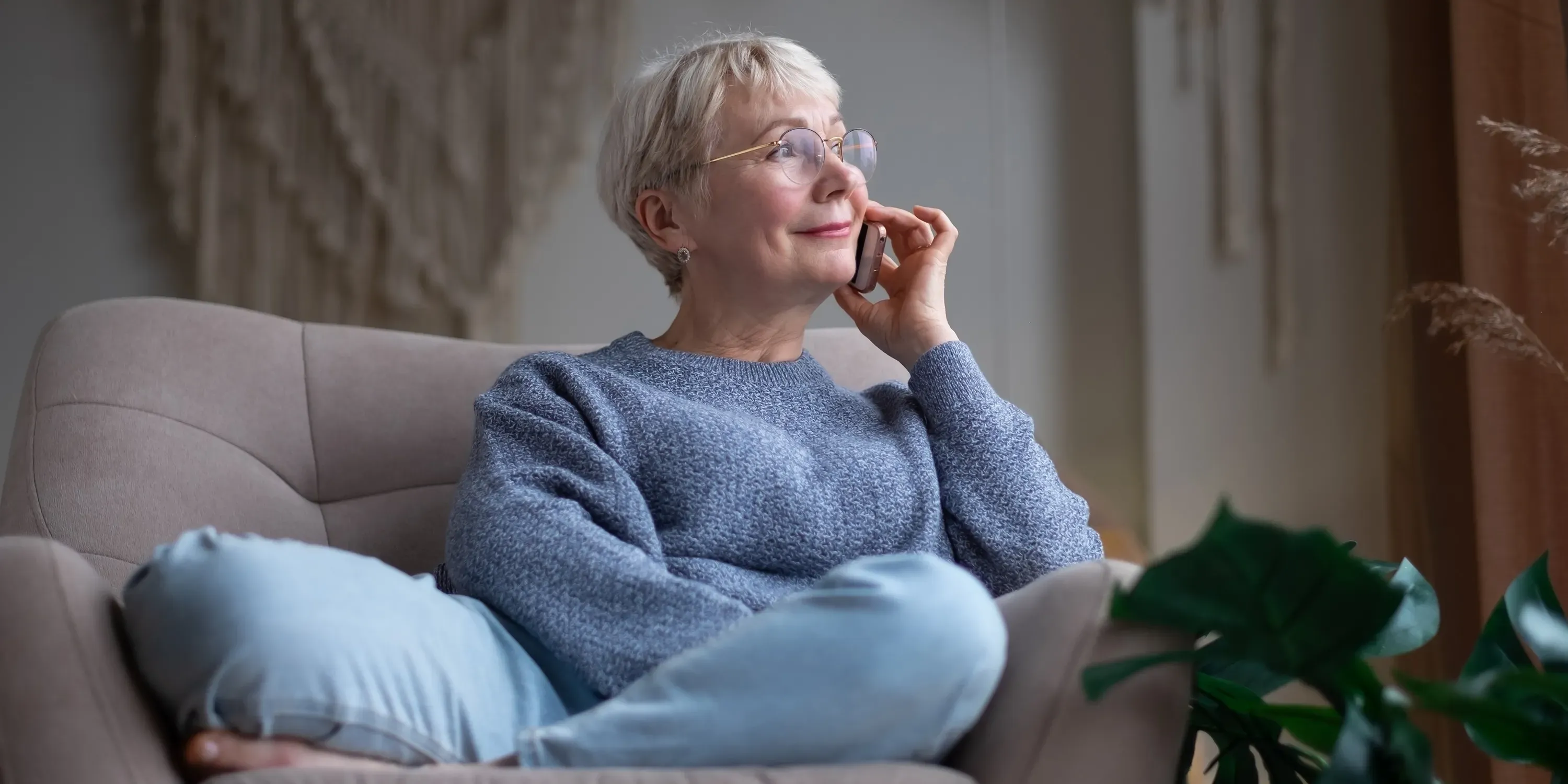 Ældre kvinde på sofa taler i telefon.