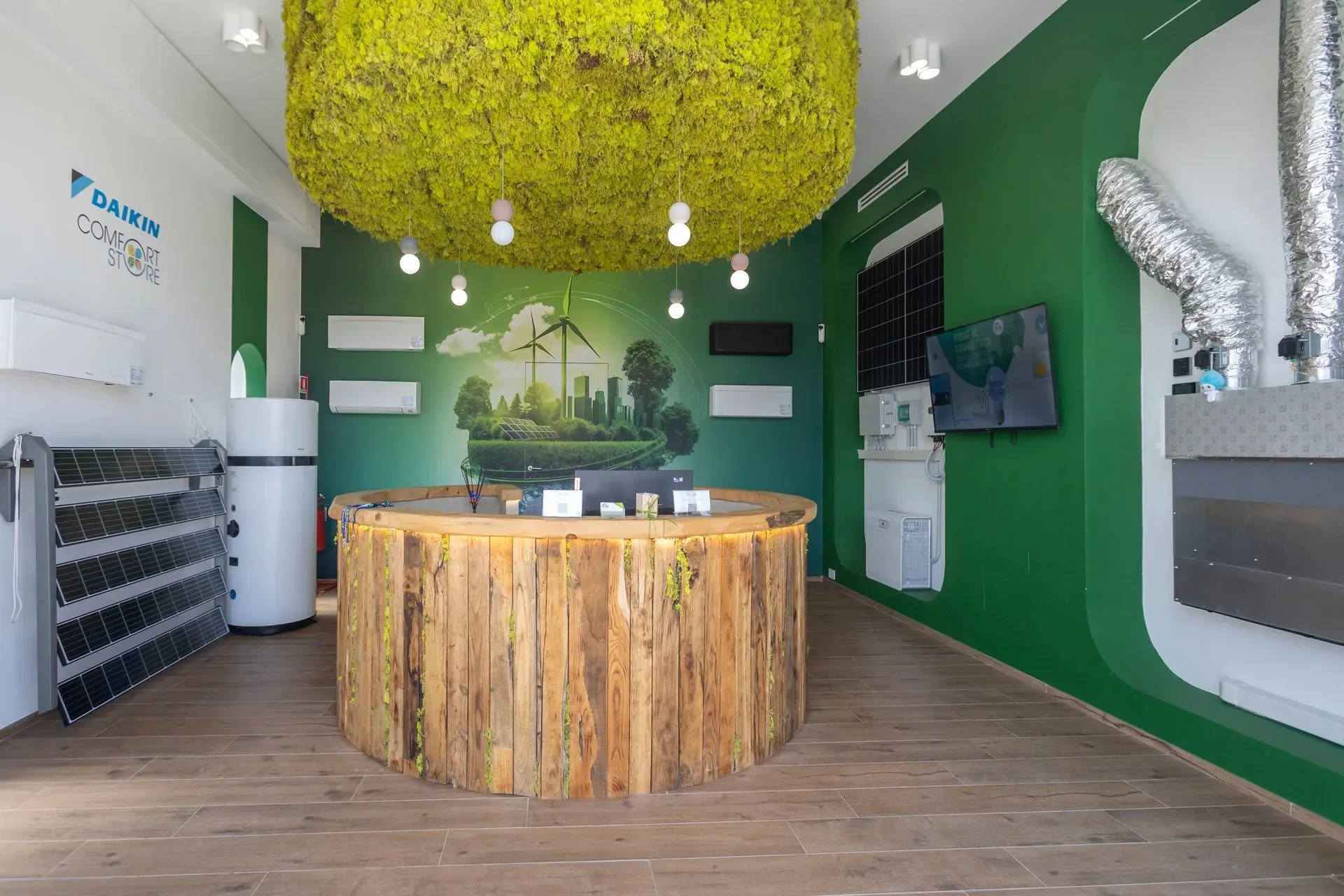 Banco reception circolare in legno in uno showroom a tema verde con soffitto di muschio.