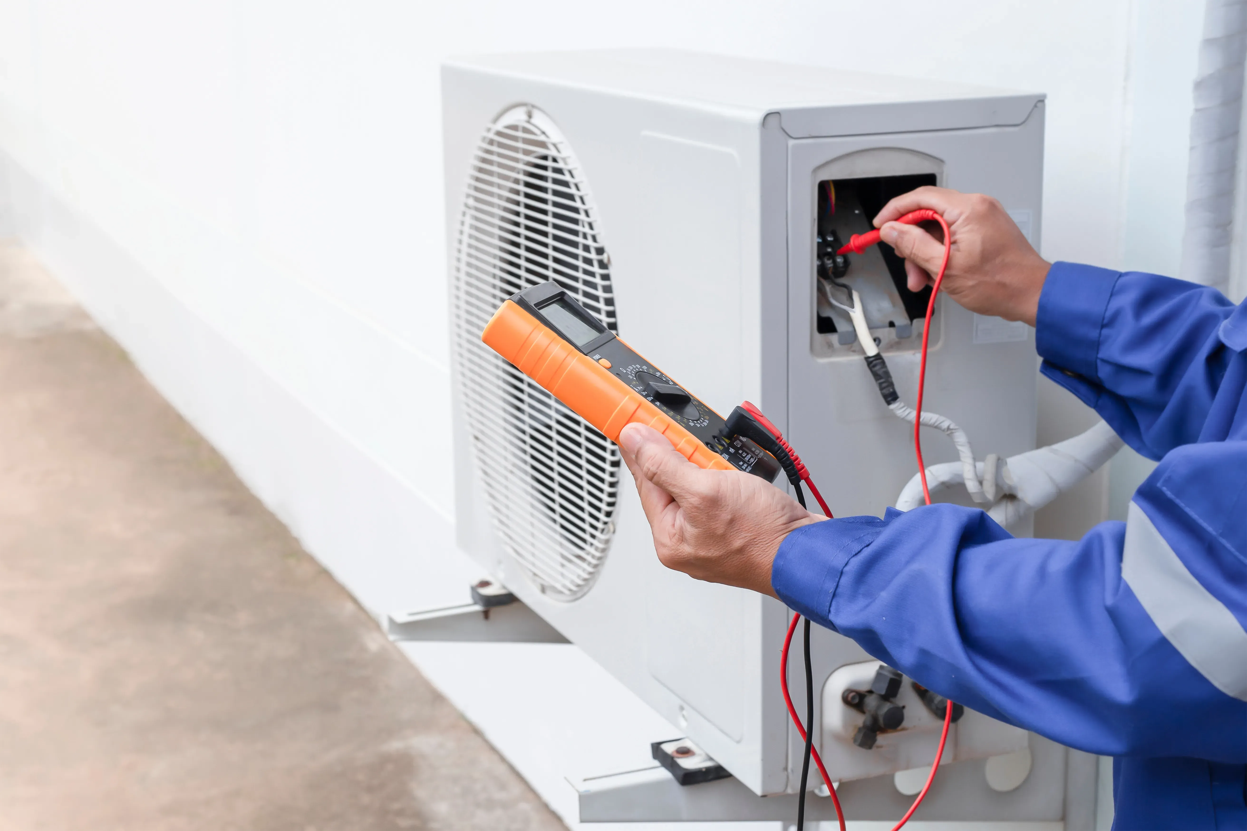 Tekniker bruger multimeter til at teste varmepumpeanordning.