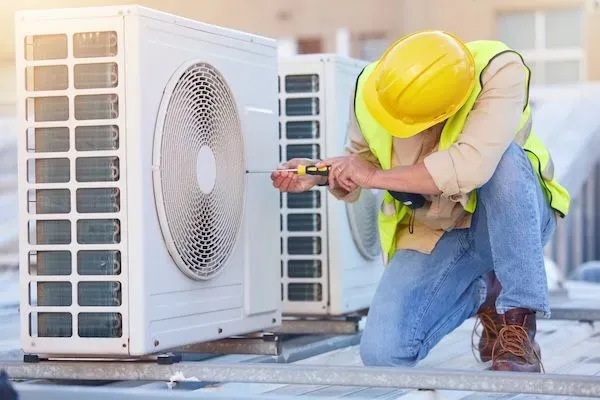Tecnico HVAC che usa un cacciavite su un'unità di condizionamento dell'aria.