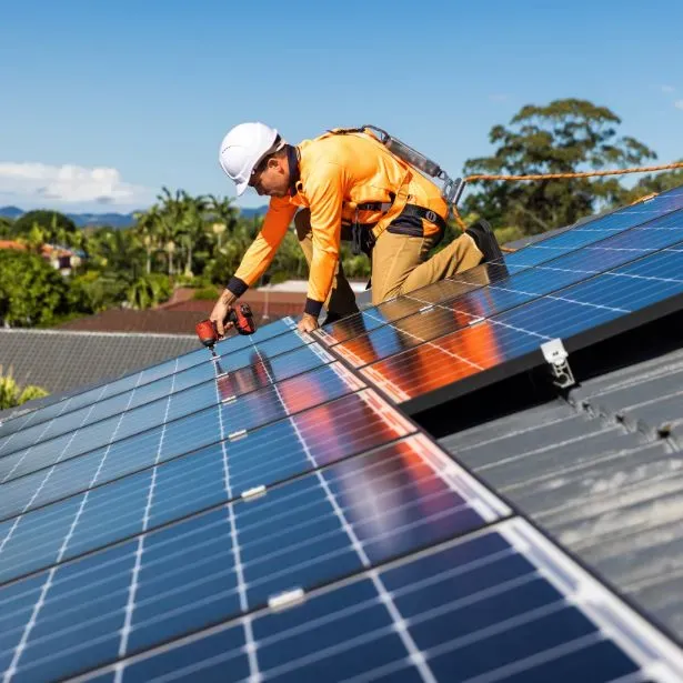 Operaio con casco che fissa un pannello solare sul tetto.