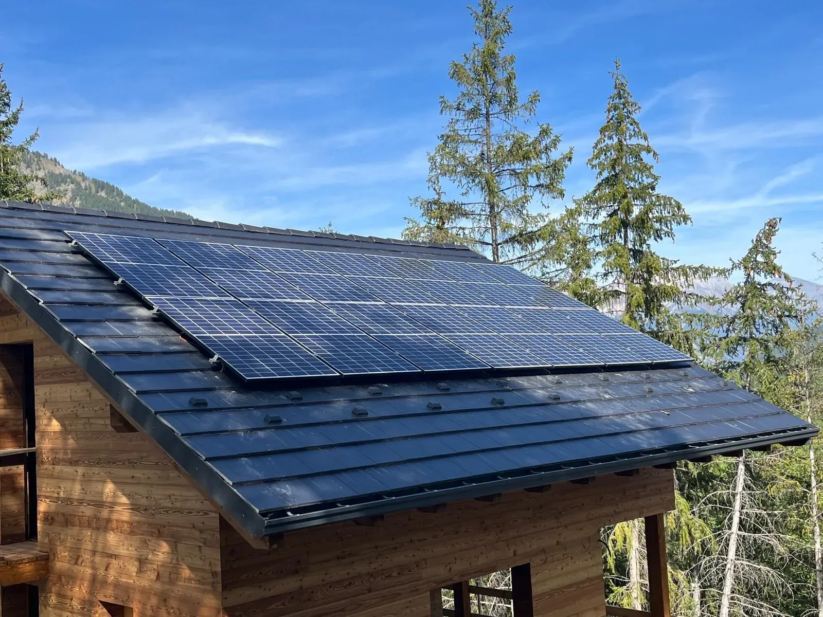 Pannelli solari installati sul tetto inclinato di una casa in legno.