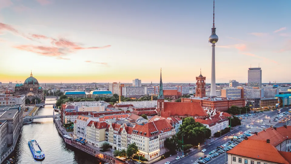 Panoramablick über die Berliner Innenstadt bei Sonnenuntergang mit Fernsehturm, Berliner Dom, Rotem Rathaus und einem Schiff auf der Spree.