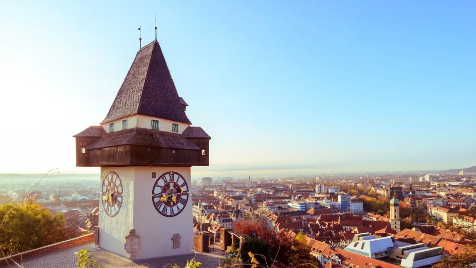 Historischer Uhrturm mit Kegeldach über Graz.