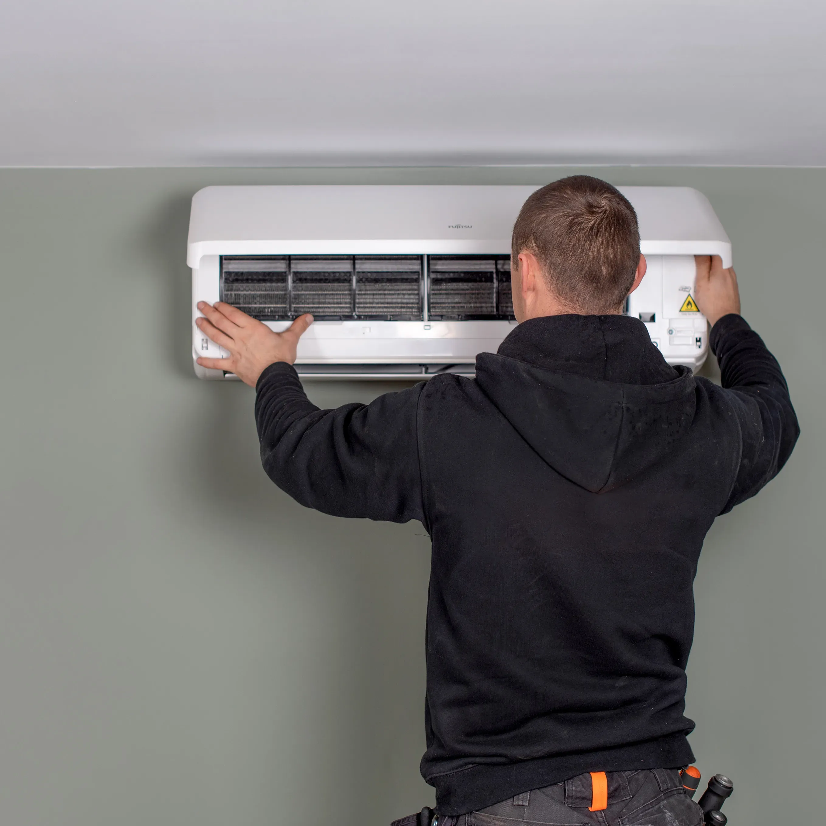 A technician installing a wall-mounted air conditioning unit.