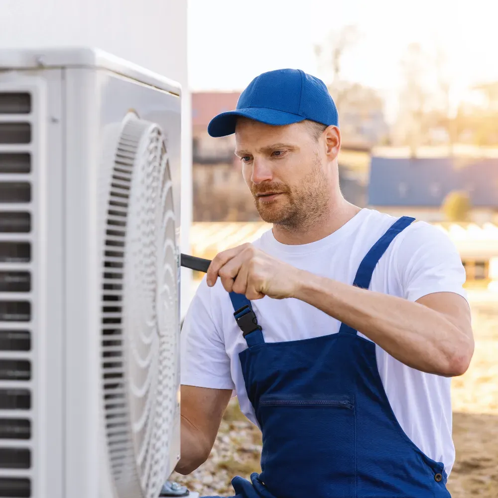 HVAC technician using a wrench to service an air conditioning unit.