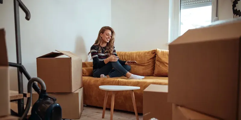 Kvinde sidder på sofa omgivet af flyttekasser.