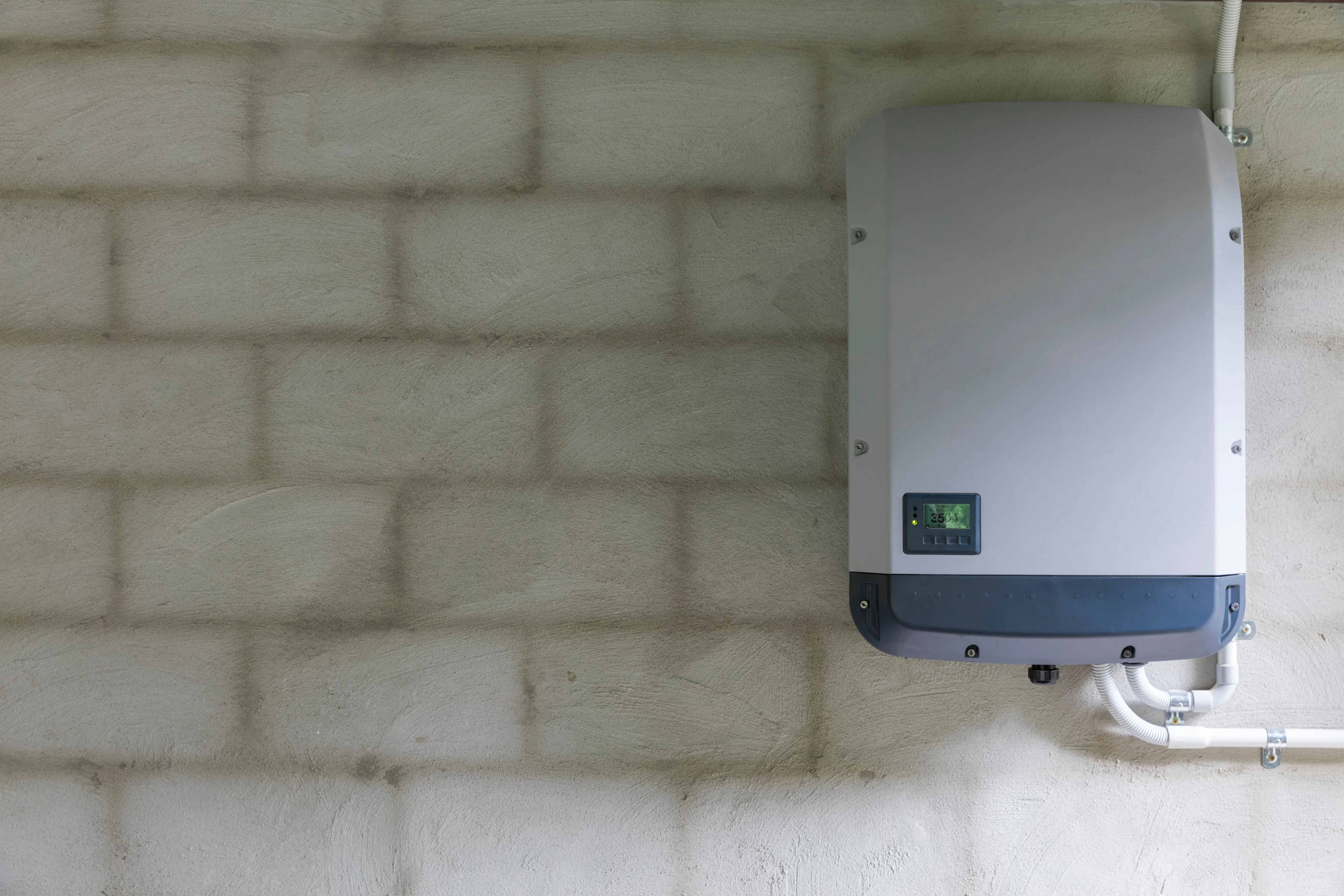 Solarwechselrichter an Betonwand montiert mit digitaler Anzeige.