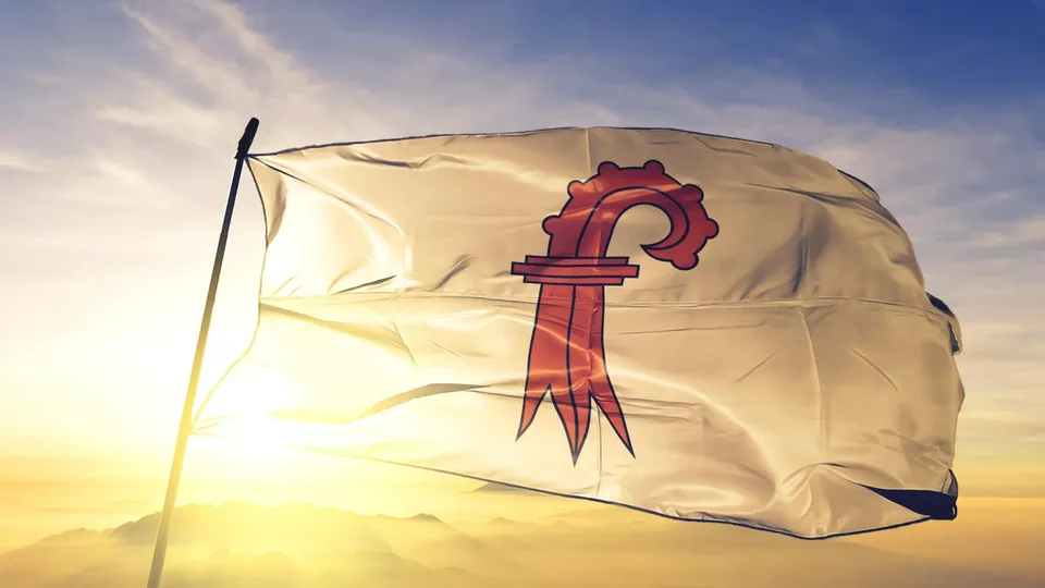 Eine weiße Flagge mit Wappen des Kantons Basel-Landschaft bei Sonnenuntergang wehend.