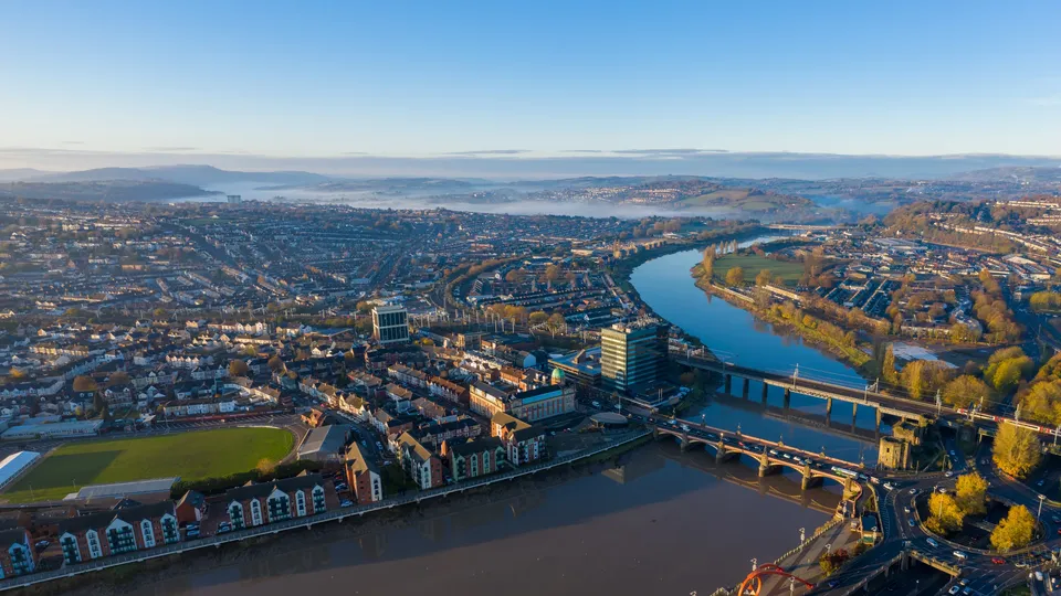 Aerial view of Newport city with river, bridges, and surrounding landscape.