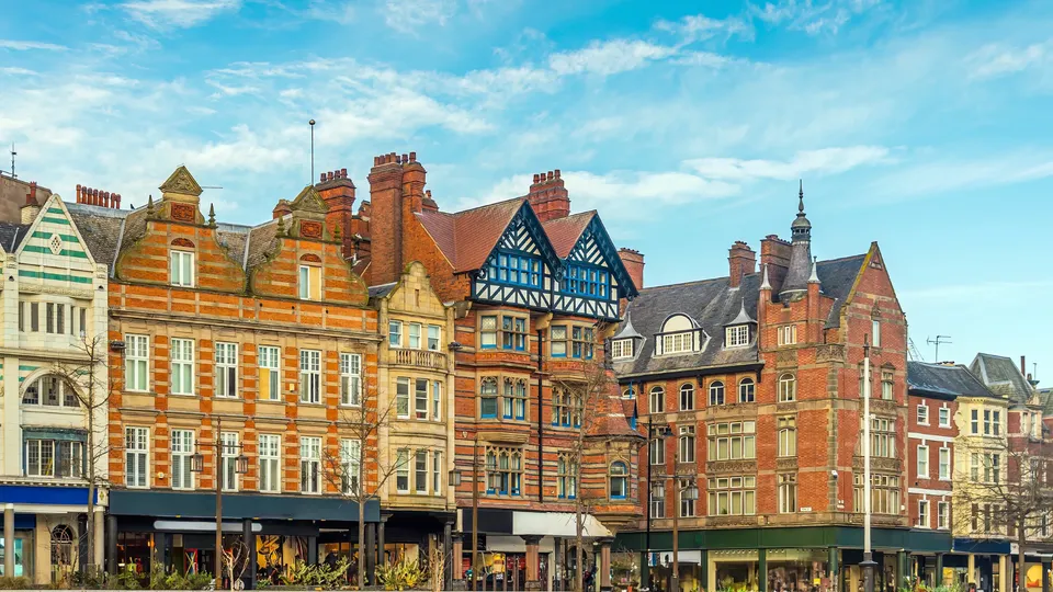 Row of Victorian and Tudor-style buildings with shops on ground floor.
