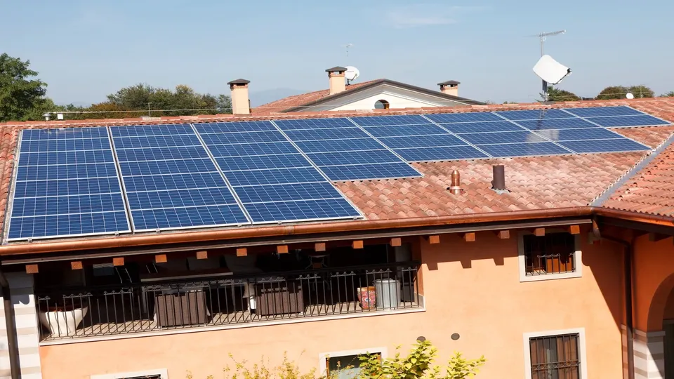 Pannelli solari installati su tetto residenziale con coppi in terracotta.