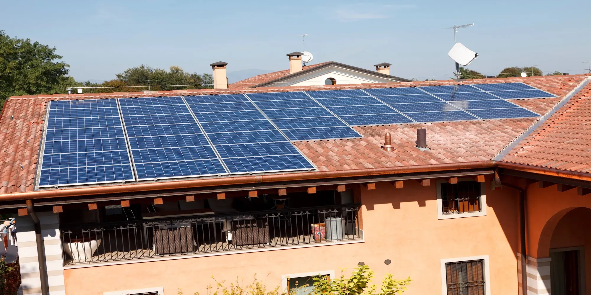 Pannelli solari installati su tetto residenziale con coppi in terracotta.