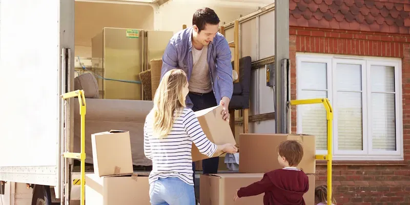 Familie pakker flyttekasser ud af flyttebil.
