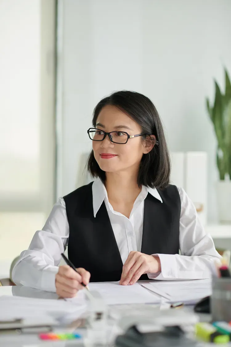 Woman at desk writing on documents.
