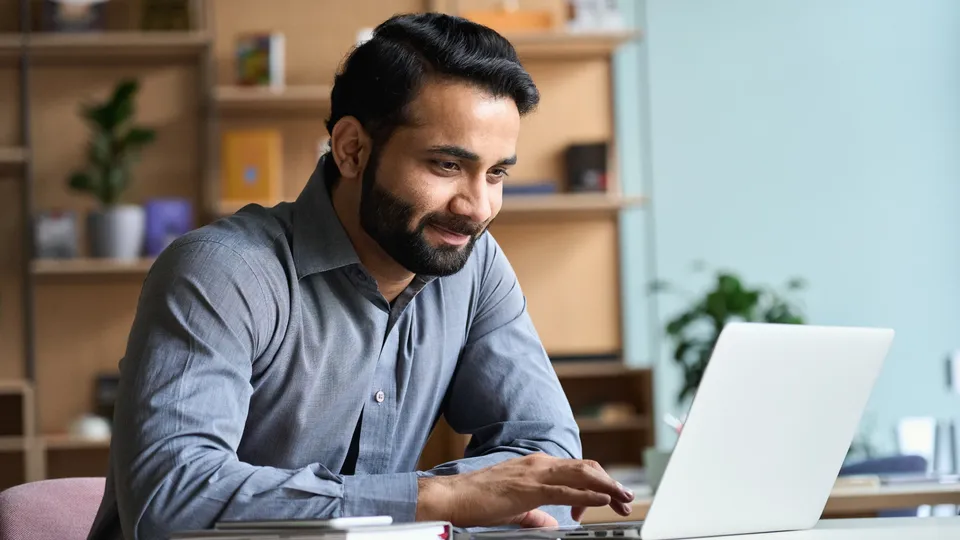 Man working on laptop at desk in office.
