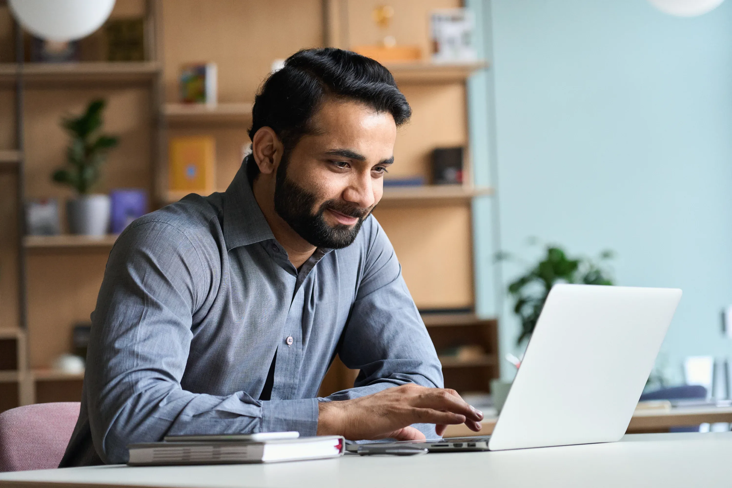 Man working on laptop at desk in office.