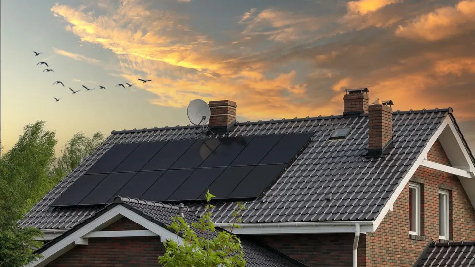 Brick house with solar panels on roof at sunset.