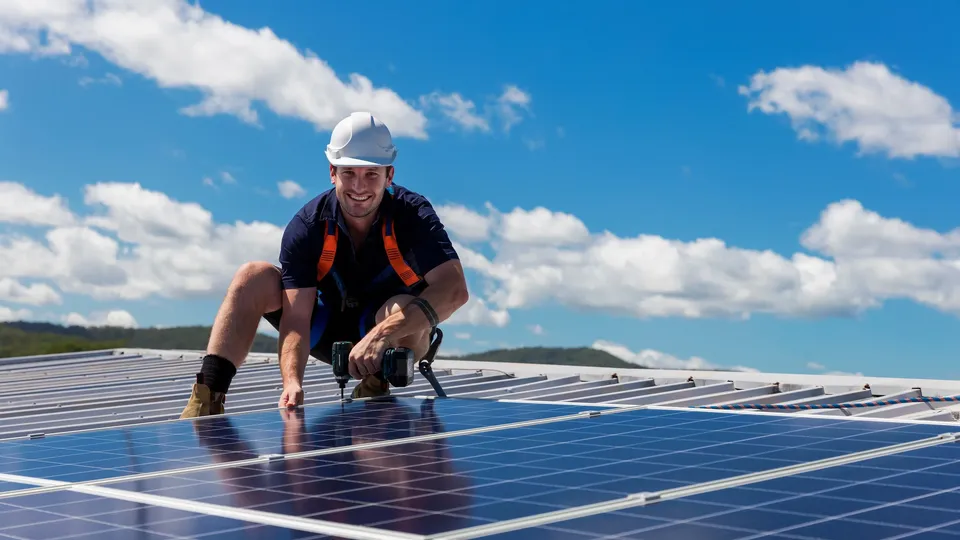 Worker installing solar panels on rooftop.