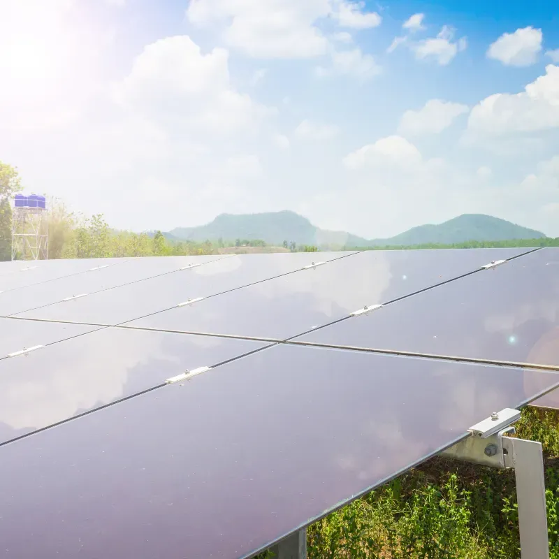 Solar panels reflecting sky with mountains in background.