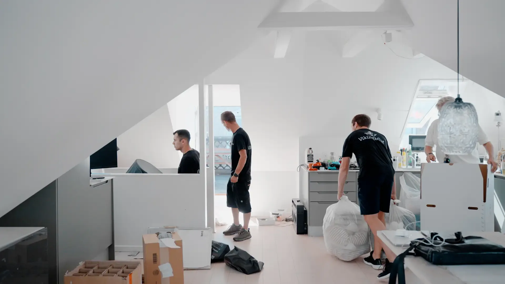 Mennesker flytter kasser og ejendele på en lys loftsetage.