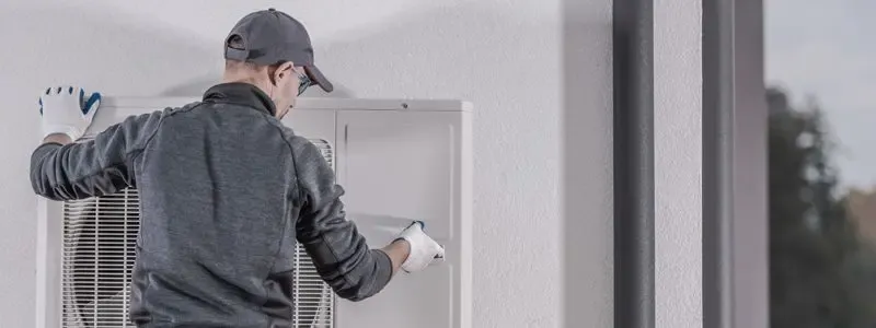Techniker installiert eine Klimaanlage an einer Außenwand.