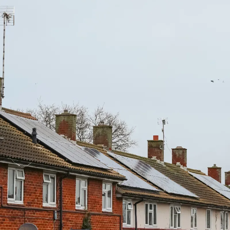 Row of brick houses with snow-covered roofs and chimneys.