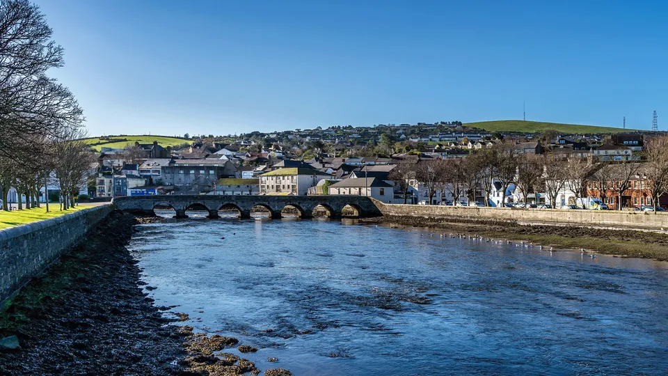 Solar panel installations. County Wicklow: Coastal town with stone bridge spanning river under clear blue sky.