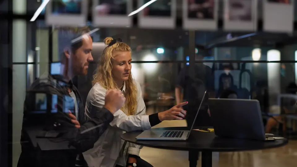 Woman and man working together at laptop in office.