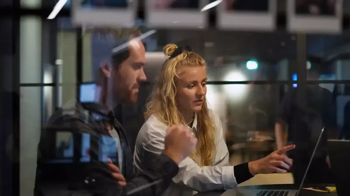 To personer der samarbejder ved en computer på et kontor