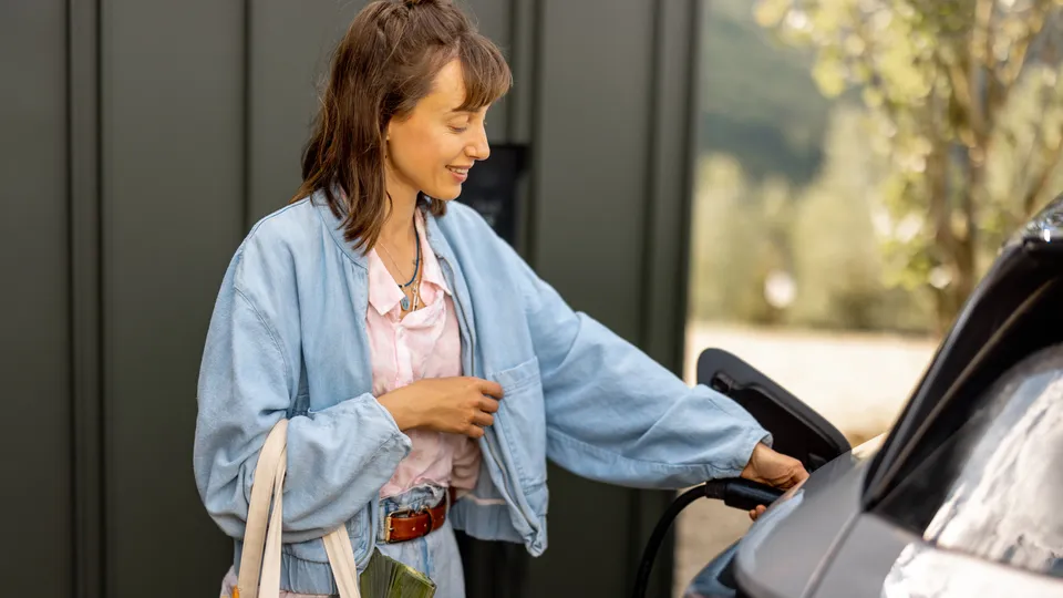 Bilde av ei dame som lader EL-bil med AC-lader