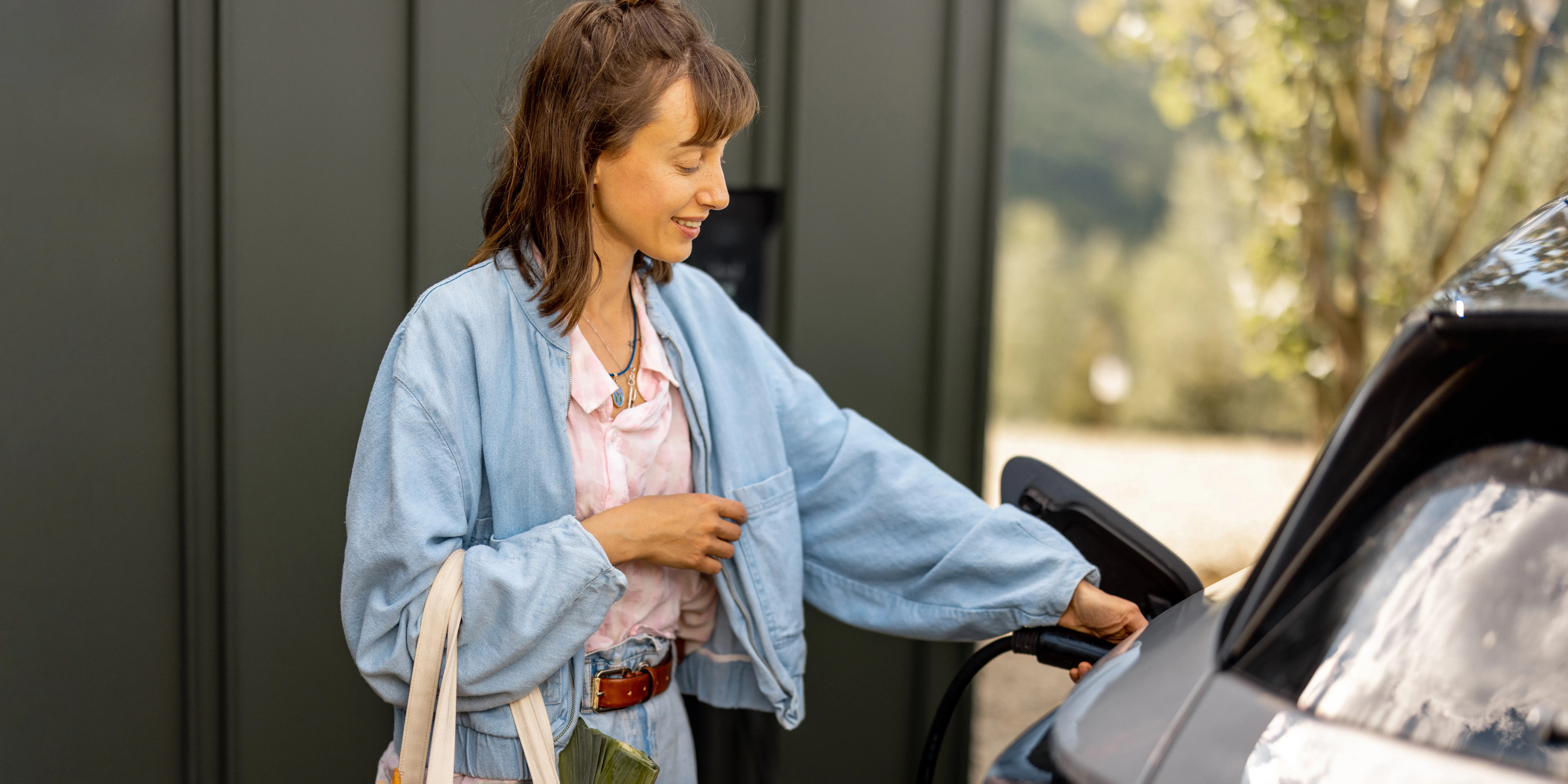 Bilde av ei dame som lader EL-bil med AC-lader