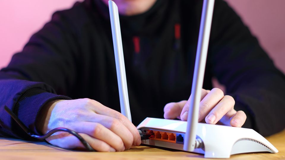 Nærbilde av en person som plugger i strømkontakten i en router.
