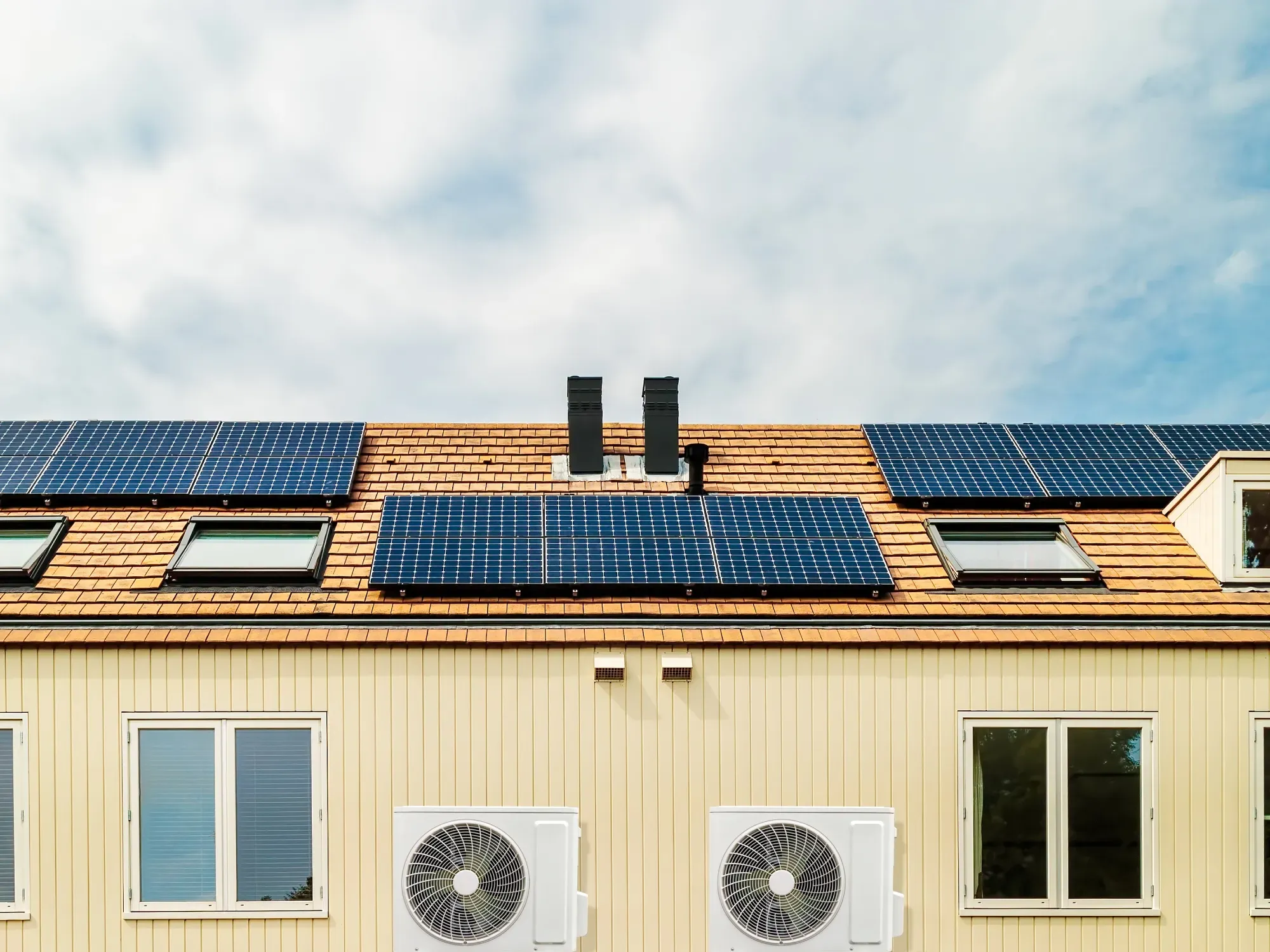 House roof with solar panels and heat pump units installed.