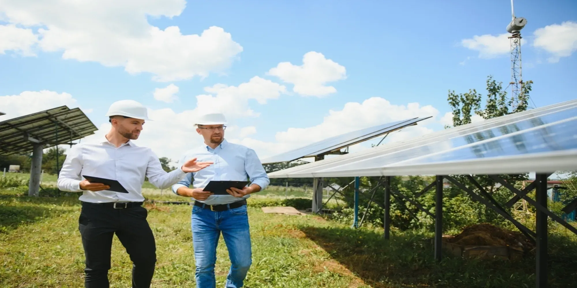 Due ingegneri con caschi di sicurezza controllano l'installazione di pannelli solari in una fattoria di energia rinnovab.