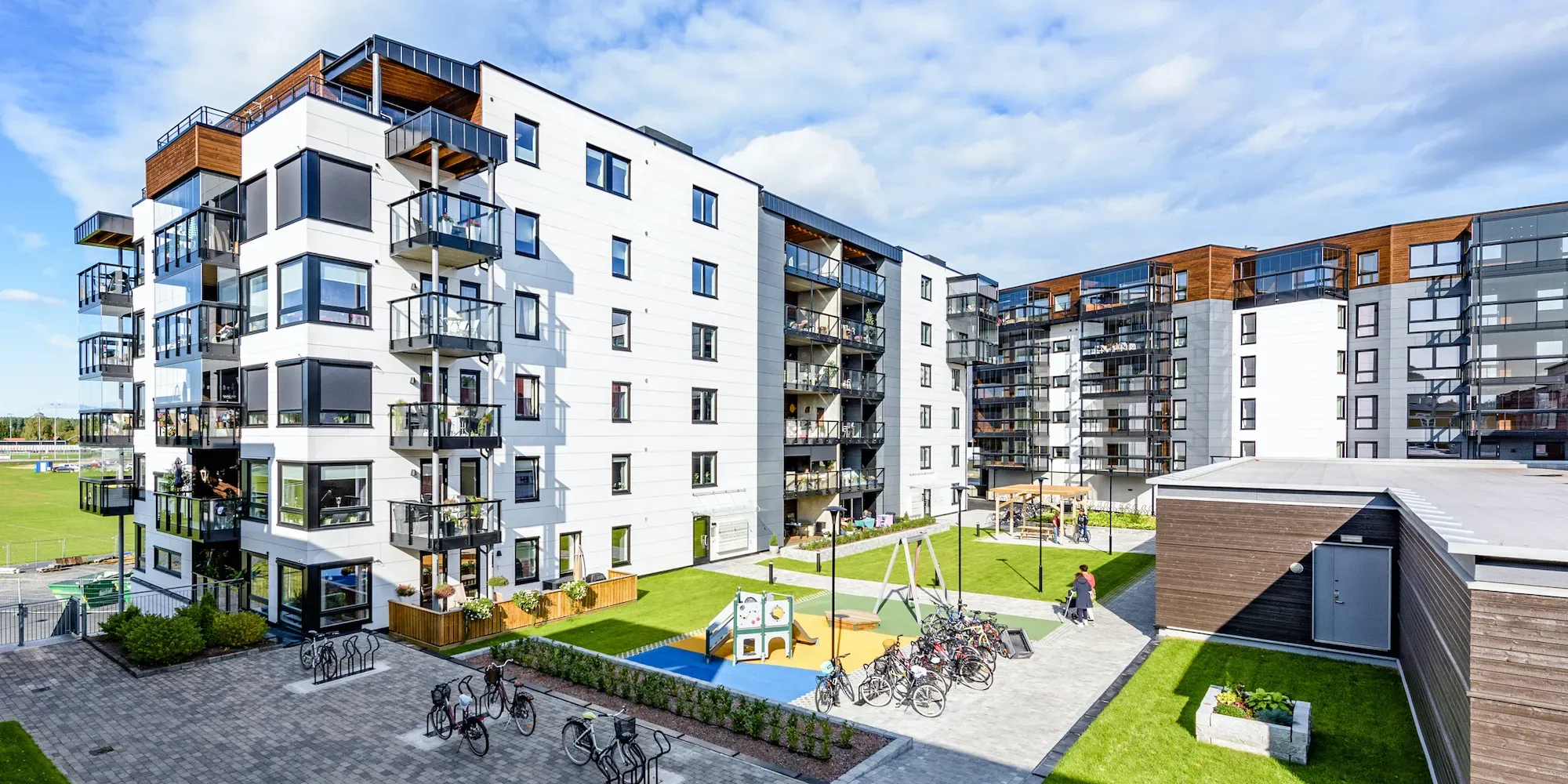 Moderne leilighetsblokk med gårdsplass, lekeplass og sykkelparking.
