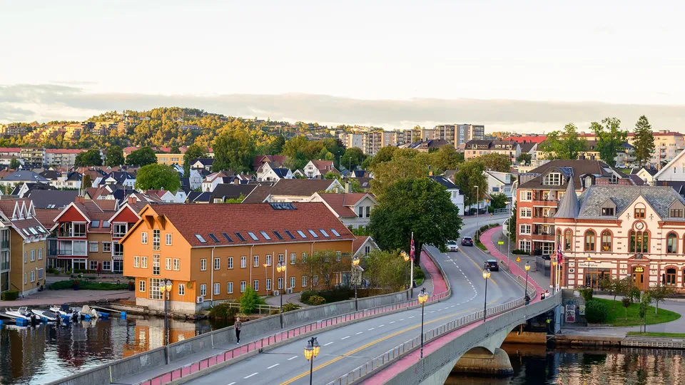 Fargerik kystby med rosa bru over elv.