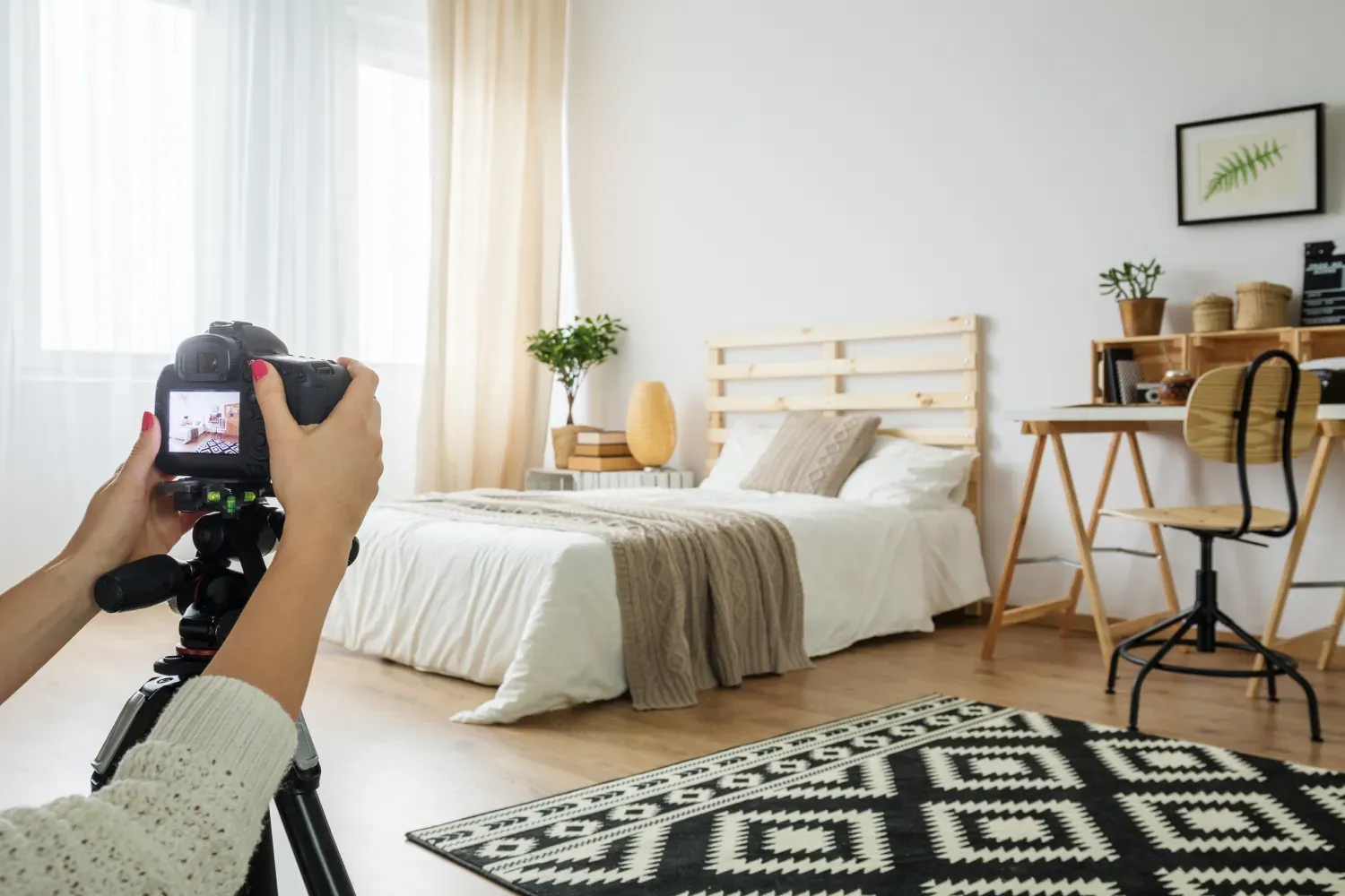 Person håller kamera på stativ och fotograferar sovrumsinredning.