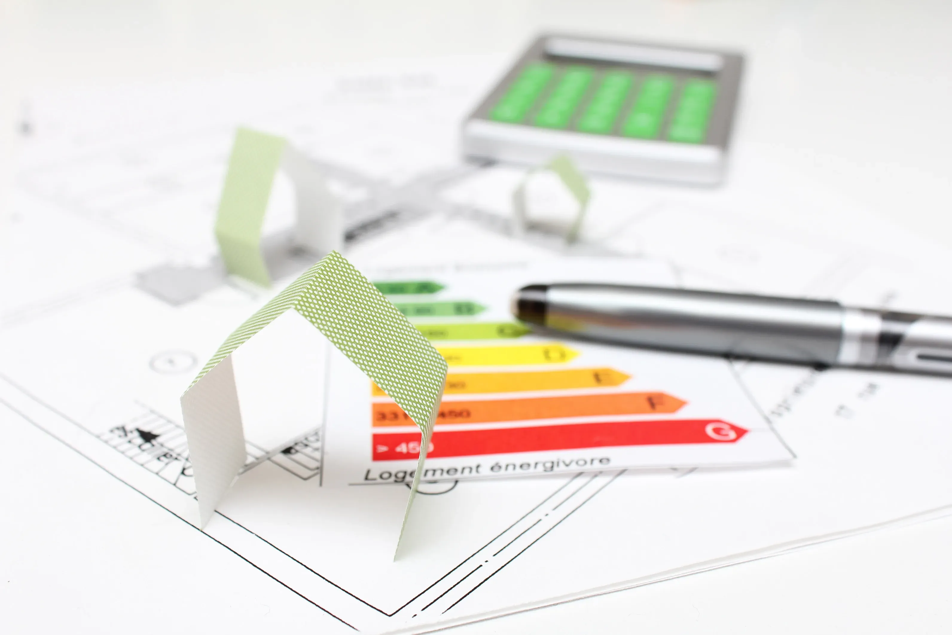 Modello di casa bianca su grafico di classificazione energetica con penna e tablet.
