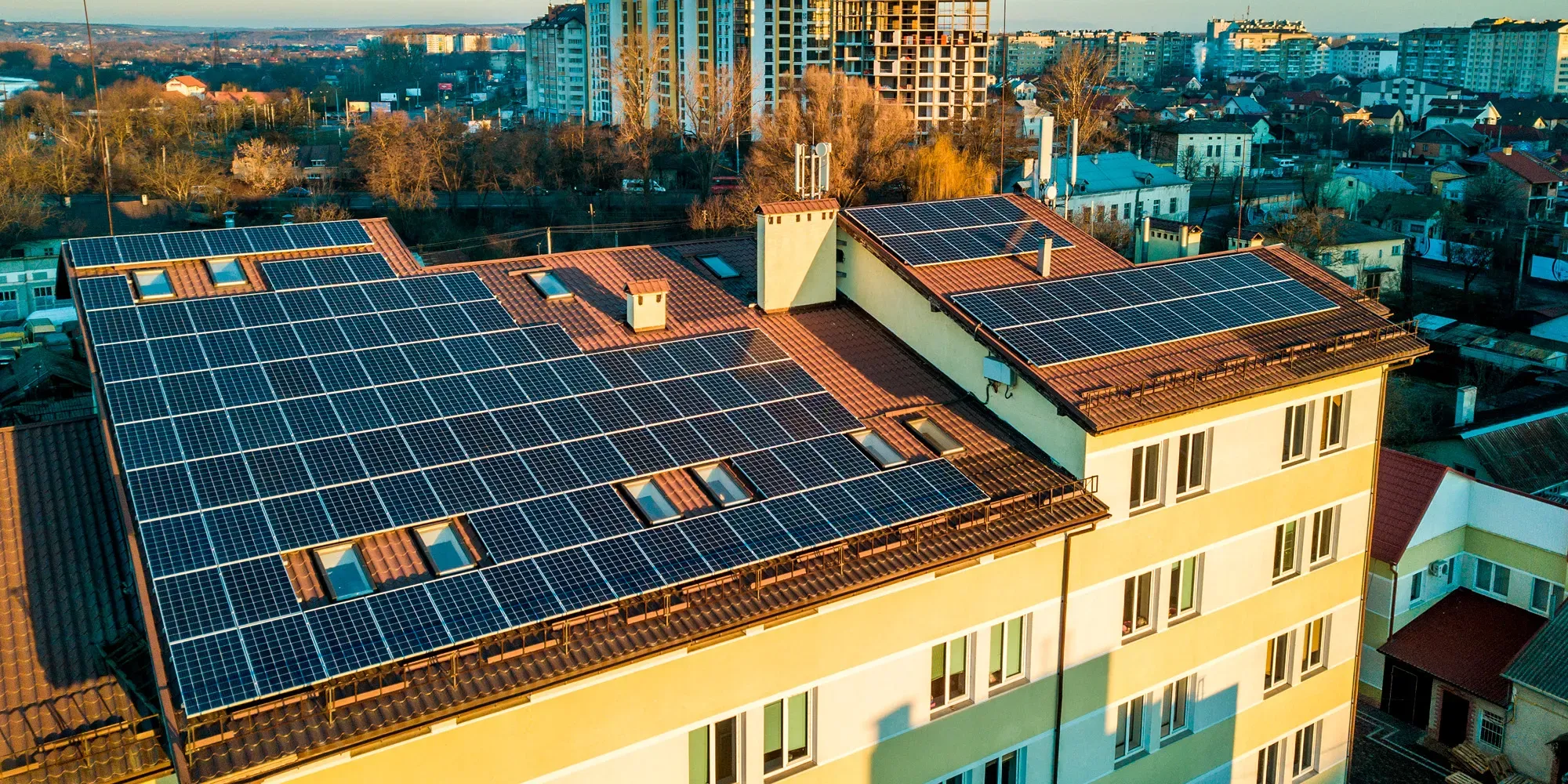 Paneles solares en azoteas de edificios residenciales con vista a un paisaje urbano.