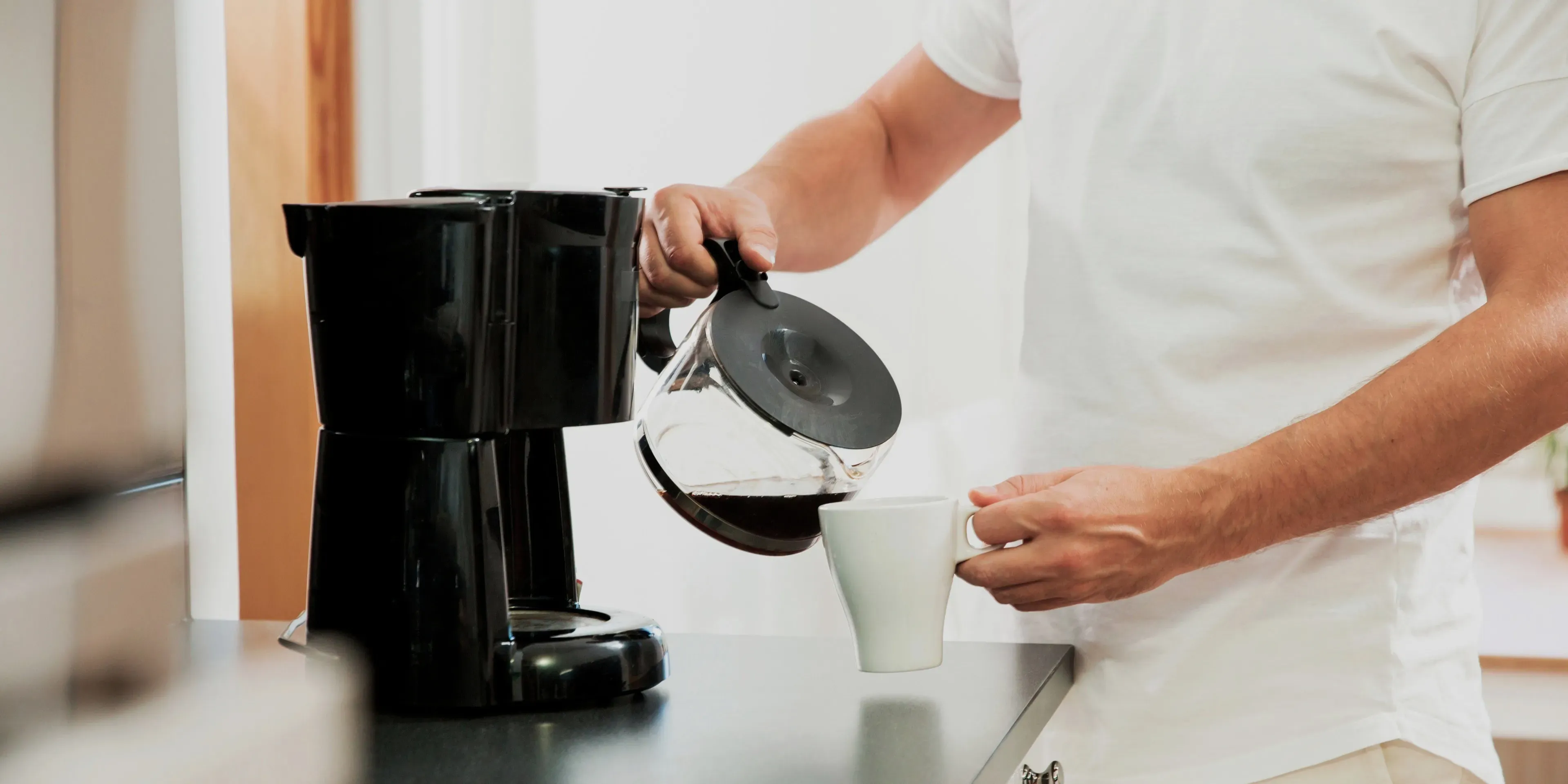 En man häller upp kaffe från en kaffebryggares kanna.