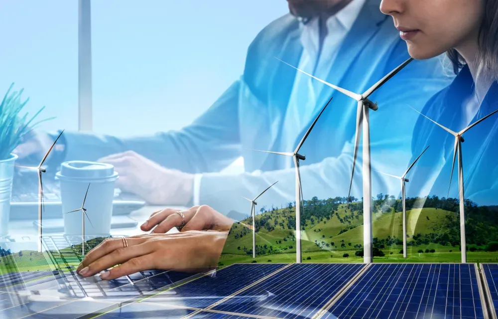 Professionisti aziendali esaminano infrastrutture di energia rinnovabile con turbine eoliche e pannelli solari.