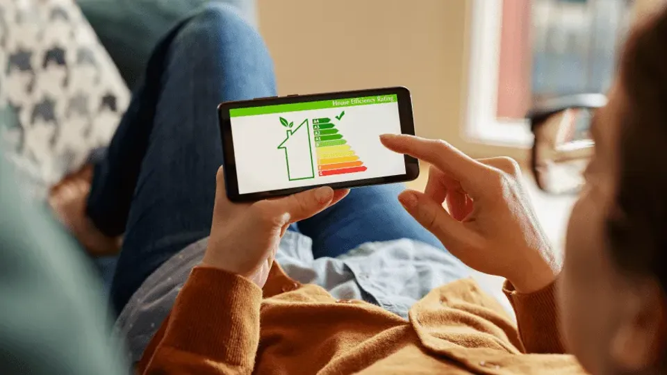 BER certificate and solar panels: Person holding smartphone displaying energy efficiency rating chart.