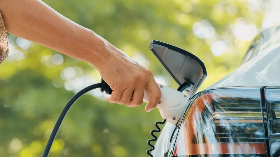 Person holder elbil-ladekabel tilsluttet til bil.