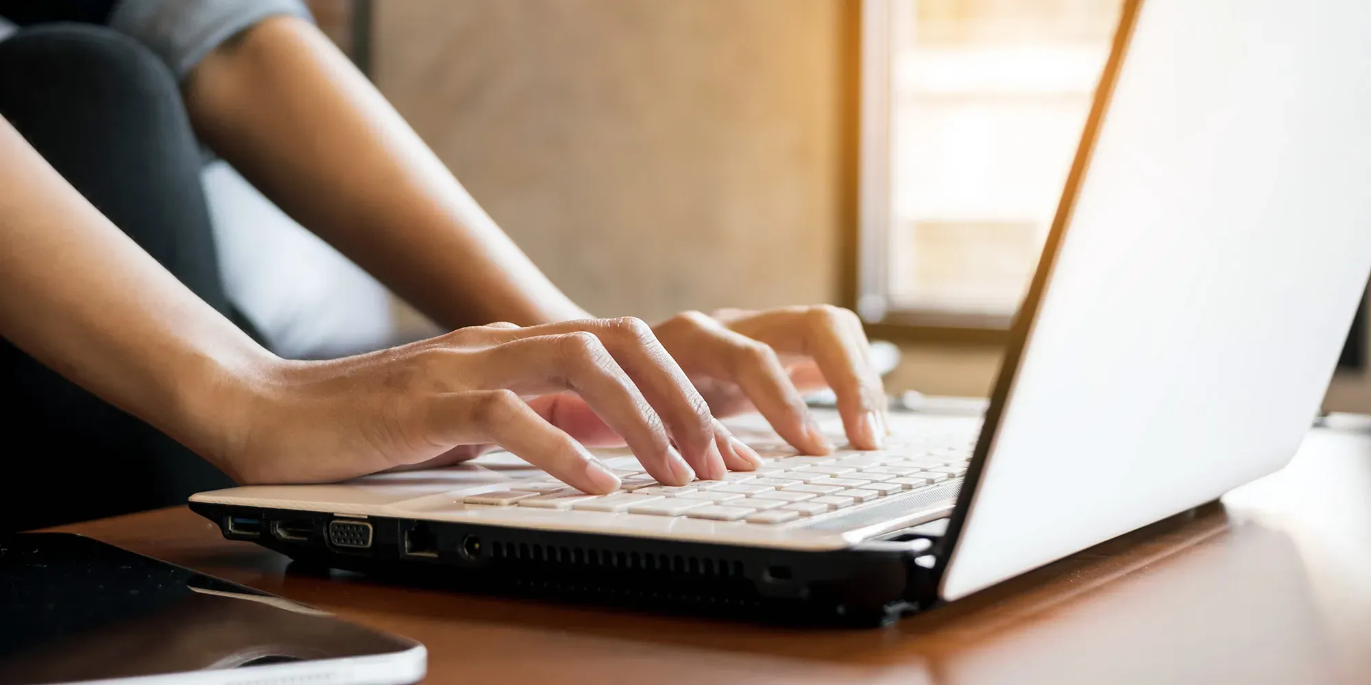 Persona escribiendo en el teclado de una laptop.