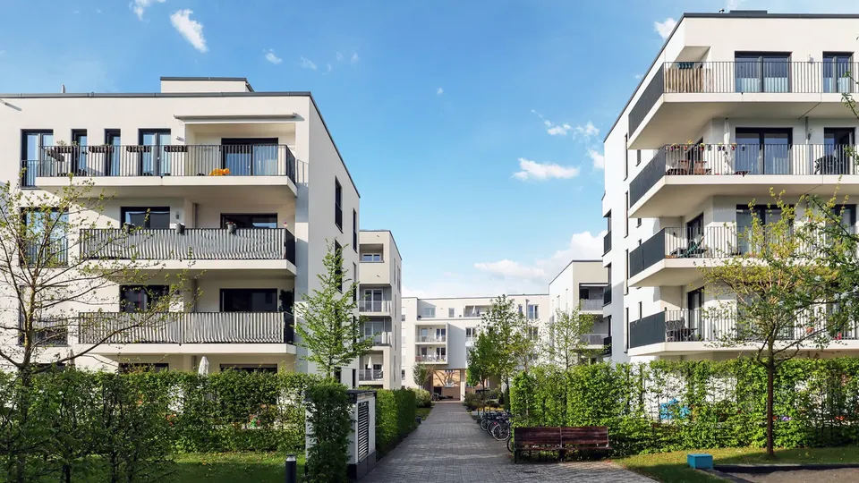 Moderne lejlighedsbygninger med altaner omkring en baggård.
