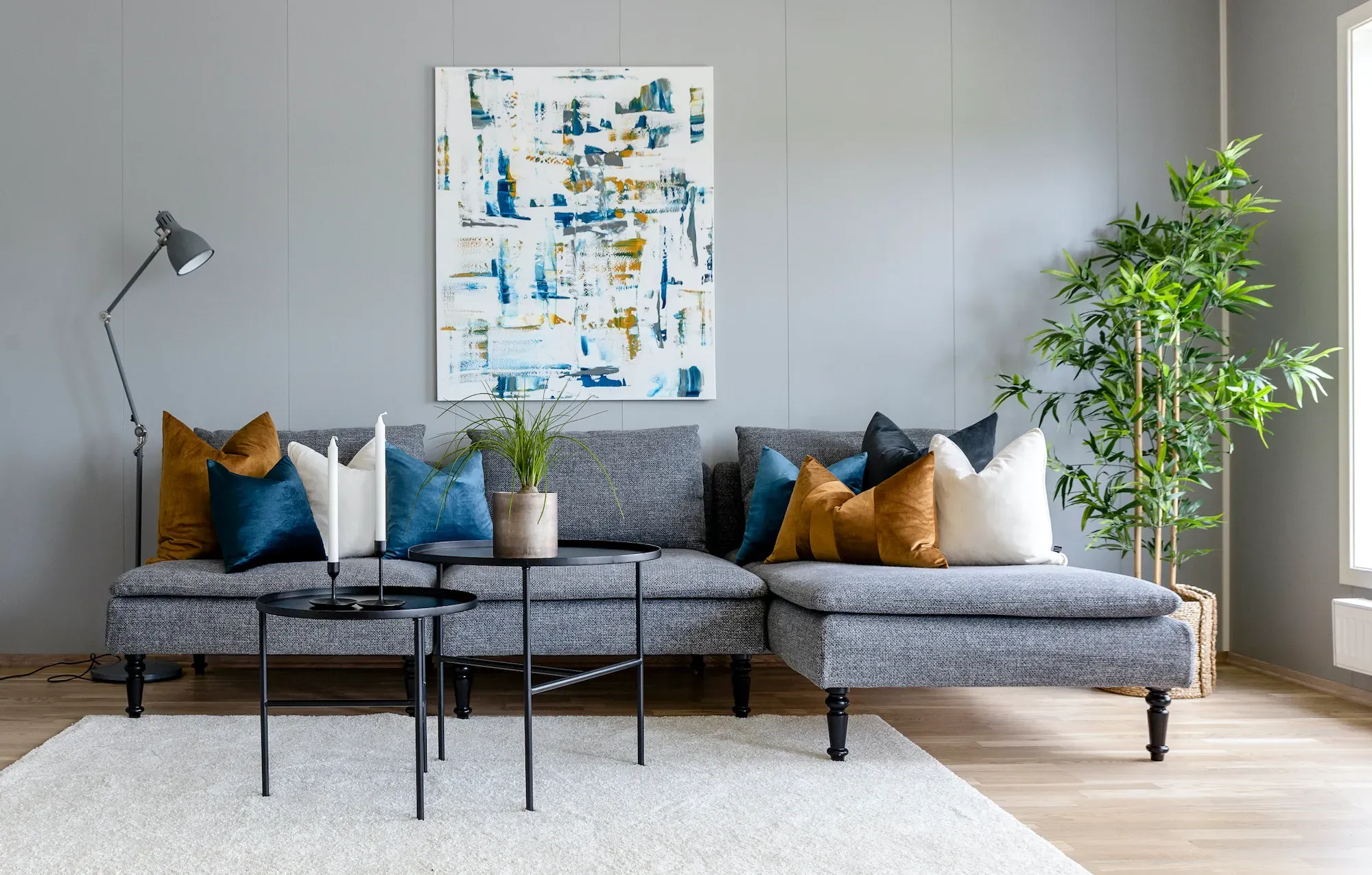 Stue med kunst på veggen og pynteputer i harmonerende farger som en del av boligstyling.