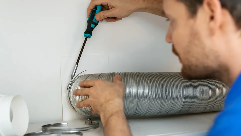 Varmepumpemontør, der fixer et rør på en ventilationsvarmepumpe