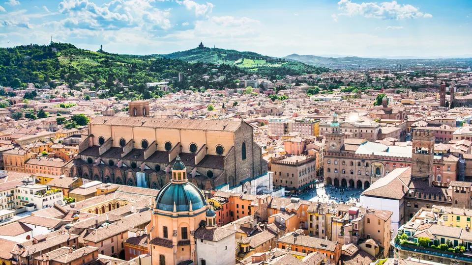 Vista aerea del centro storico di Bologna con chiesa a cupola e edifici con tetti in terracotta.